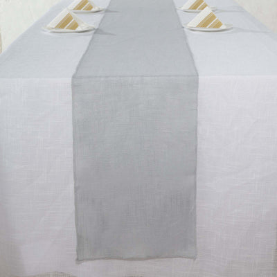 Gray table runner on a white tablecloth with plates arranged above.