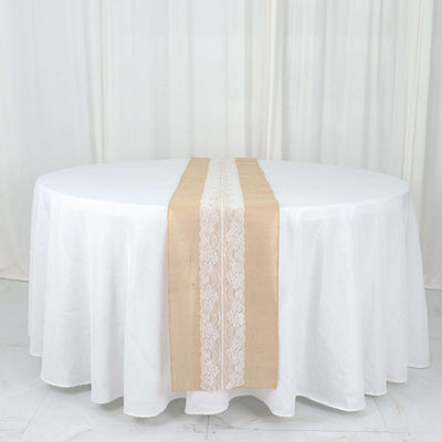Round table with a beige lace table runner on a white tablecloth.