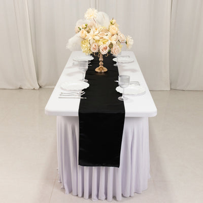 Elegant table setting with black runner and floral centerpiece.