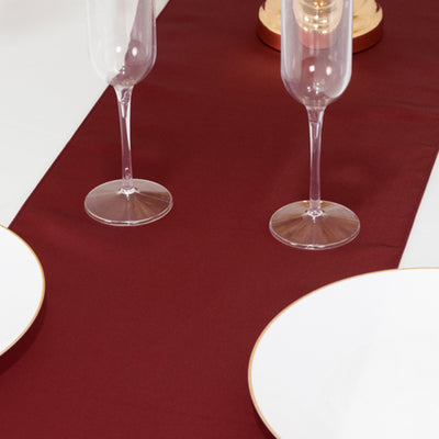 Elegant burgundy table runner with white plates and champagne flutes.