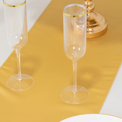 Gold-rimmed champagne flutes on a golden table runner.