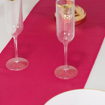 Elegant pink table runner with clear champagne flutes and a gold candle holder.