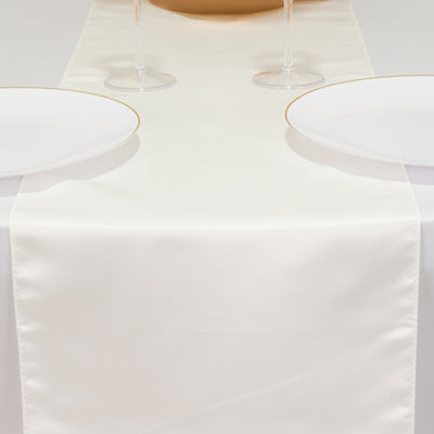 Elegant cream table runner on a dining table with plates and glasses.