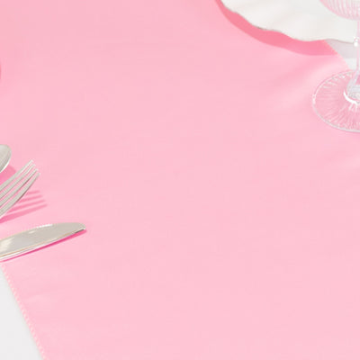 Pink tablecloth with silver cutlery on a plain backdrop.