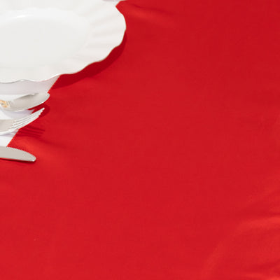 White scalloped plate on a vibrant red tablecloth.