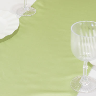 Green table runner with elegant glassware on a white backdrop