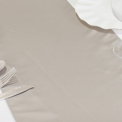 Elegant beige table runner with silver cutlery and white plate.