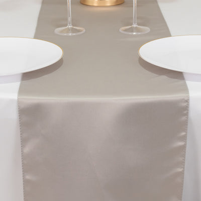 Elegant beige table runner with two white plates and glasses on a dining table.
