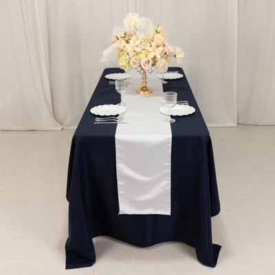 Elegant navy table setting with white runner and floral centerpiece.