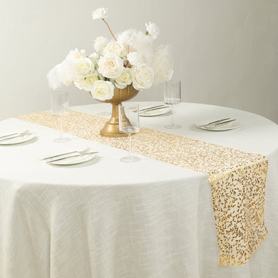 Elegant gold leaf table runner on a round dining table with floral centerpiece.