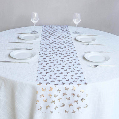 Butterfly-patterned table runner on a white table with plates and glasses.