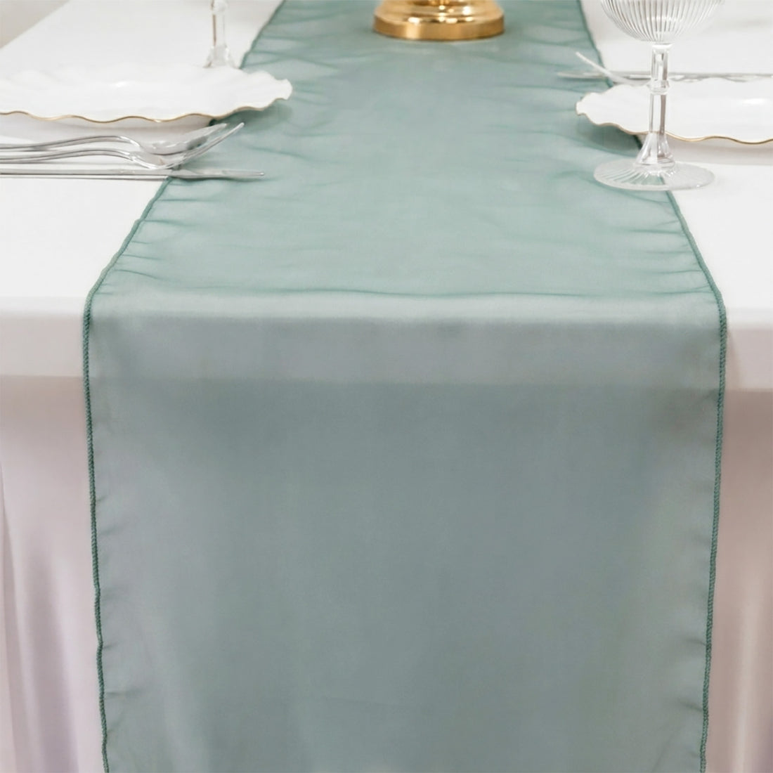 Mint green sheer table runner on a white dining table with elegant tableware