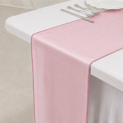 Pink satin table runner on white table with silver cutlery, elegant dining decor