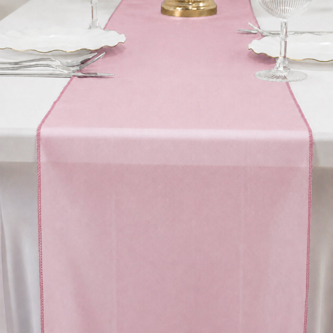 Pink table runner on a white table setting with elegant glassware and plates