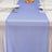 Blue sheer table runner on a white dining table with glassware and plates.