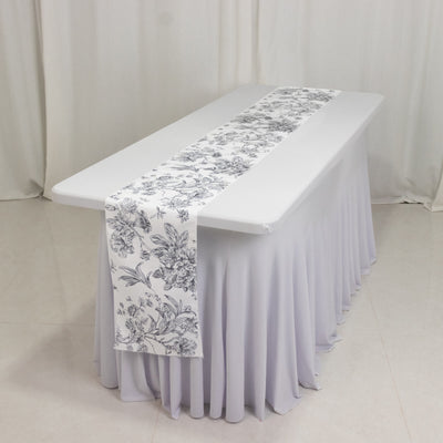 Floral table runner on a white tablecloth in a styled setting.