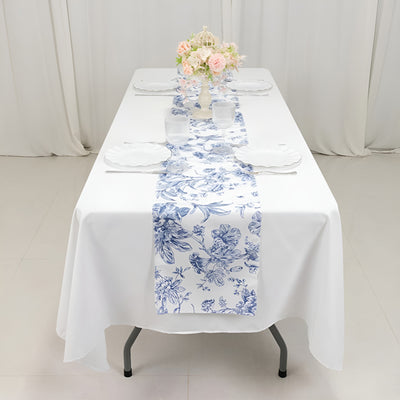 Floral table runner on a white table with decorations and plates.