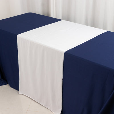 Navy table with a white table runner in a studio setting.