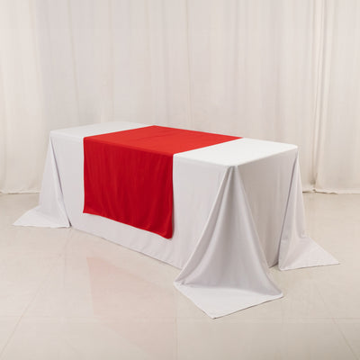 White table with red table runner on a plain backdrop