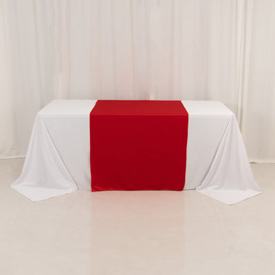Red table runner on a white tablecloth in a studio setting.