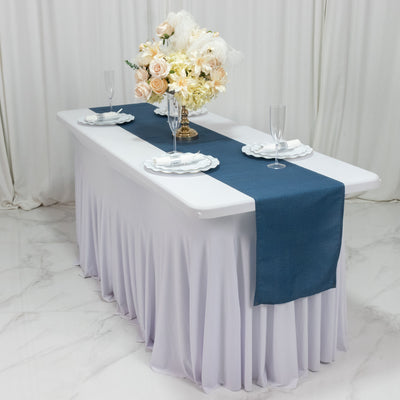 Elegant table setting with a blue runner, white plates, and floral centerpiece.