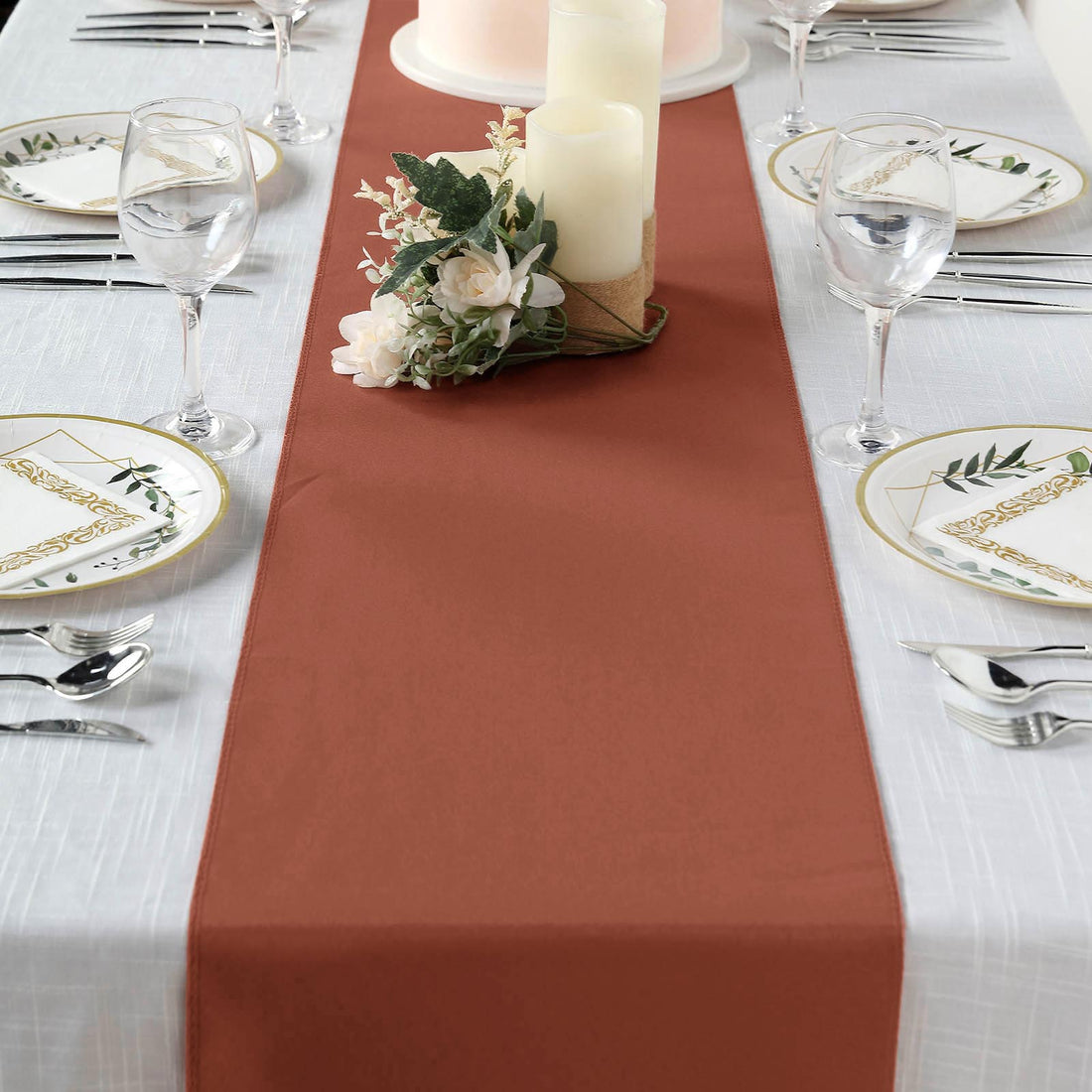 Brown table runner on a beautifully set dining table with candles and floral decor.