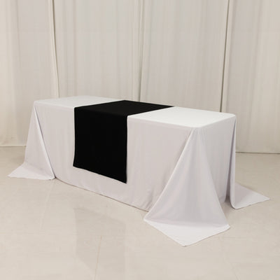White table with black table runner on plain backdrop