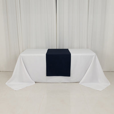 White table with a navy blue table runner in a studio setting.