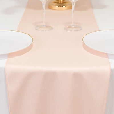 Blush pink table runner on a white table setting with plates and glasses