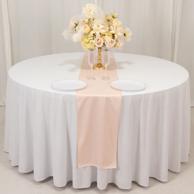 Elegant round table set with floral centerpiece and pale pink table runner.