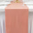 Peach table runner on a white table setting with elegant glassware.