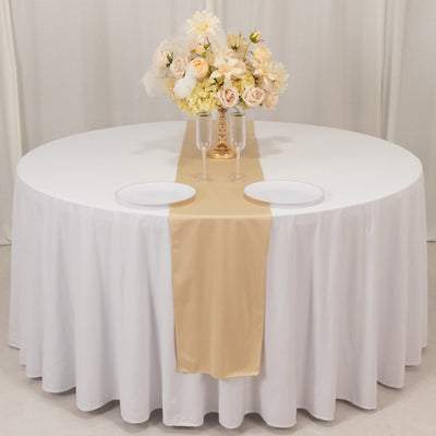 Elegant round table set with a floral centerpiece and gold runner.