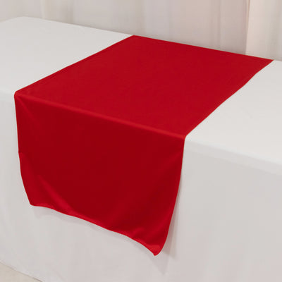 Red table runner on a white tablecloth for elegant dining setups.