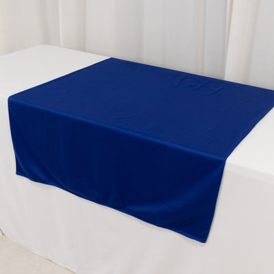 Blue tablecloth draped on a white table in a studio setting.