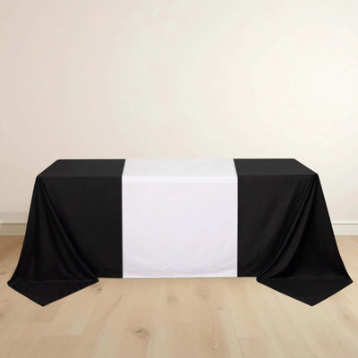 Black and white tablecloth draped over a table on a light wooden floor.