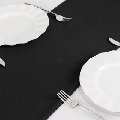 Elegant white plates with silver-edged detail and forks on a black tablecloth.