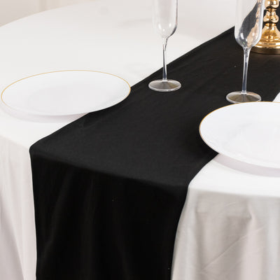 Black table runner on a white tablecloth with elegant dinnerware.