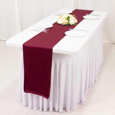 Elegant table setup with a burgundy runner and floral centerpiece.
