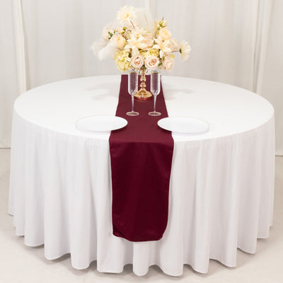 Elegant round dining table set with white linens and floral centerpiece.