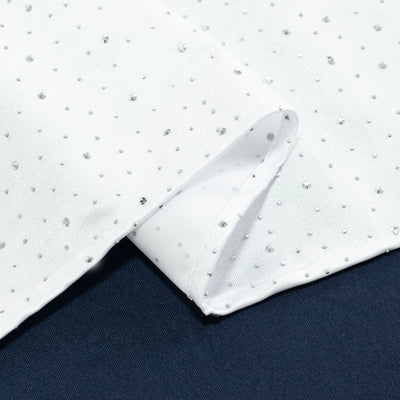 White fabric with silver sequins on a dark background.