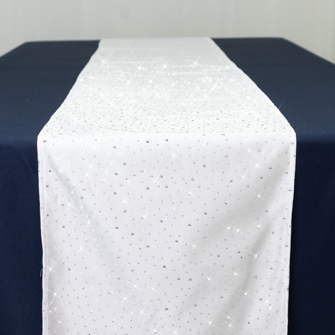 White table runner with silver sparkles on a navy blue table.