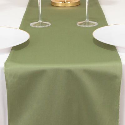 Olive green table runner on a dining table with white plates and wine glasses.