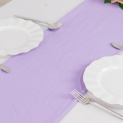 Elegant table setting with white plates and silver cutlery on a lavender tablecloth.