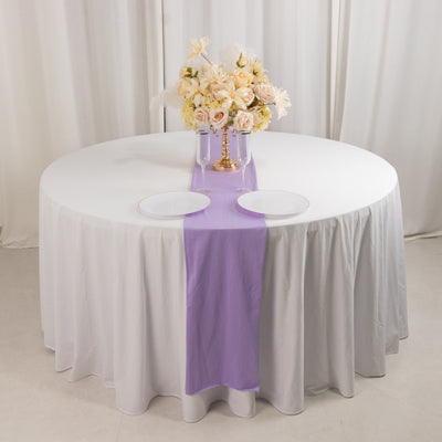 Round table set with a lavender runner and floral centerpiece.