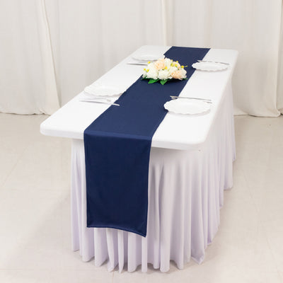 Navy table runner on a white table with plates and floral centerpiece.