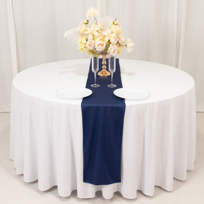 Elegant round dining table set with floral centerpiece and navy table runner.