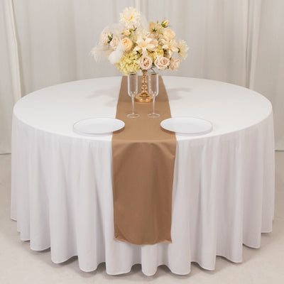 Elegant round table set with a beige runner and floral centerpiece.