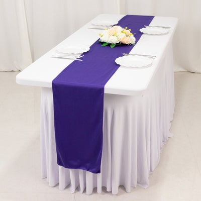 Purple table runner on a white table with plates and floral centerpiece.
