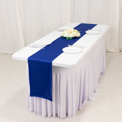 Navy blue table runner on a white table with plates and floral centerpiece.