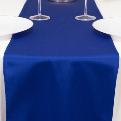 Navy blue table runner on a white table with plates and glasses.